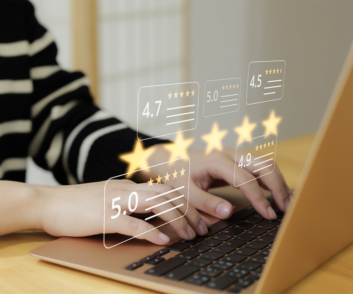 Person typing on a laptop with floating five-star review graphics and ratings, symbolizing online customer feedback—part of evolving U.S. furniture industry trends.